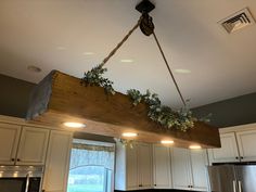 a wooden beam hanging from the ceiling in a kitchen with white cabinets and stainless steel appliances