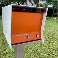 an orange and white mailbox sitting in the grass