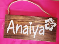 a wooden sign with the word anaiyaa written in white on a pink background