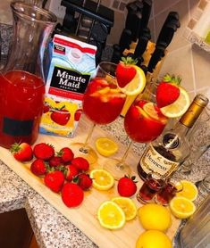 the ingredients for a strawberry lemonade punch are displayed on a kitchen counter with bottles and glasses