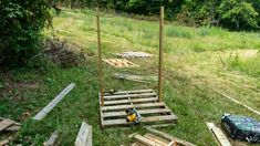 some wooden pallets are laying on the ground in front of a field and trees