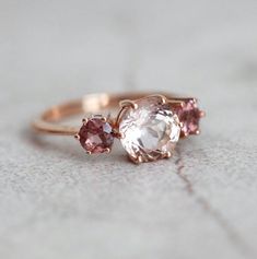 two pink and white stones are on top of a gold ring