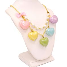 A cute and sweet statement necklace for Valentine's Day or lovecore season! This kawaii charm necklace includes Five heart shaped macaron ( macaroon ) pendants in pastel shades with a pearly finish and whipped cream center. Each necklace includes five 1" (2.5 cm) size charms hanging on a two-layered chain necklace with glass pearls on your choice of a 21" gold plated or silver plated chain. Accented with a baby pink fabric ribbon bow on one side. Necklace will be finished with a Fatally Feminine Kawaii Lovecore, Lolly Necklace, Kawaii Valentines Day, Party Cannon, Necklaces Pink, Valentines Day Candy, Kawaii Valentine, Kawaii Necklace, Pastel Heart