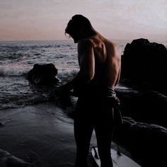 a man standing on top of a beach next to the ocean