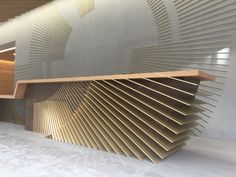 a large wooden bench sitting in front of a wall with an abstract design on it