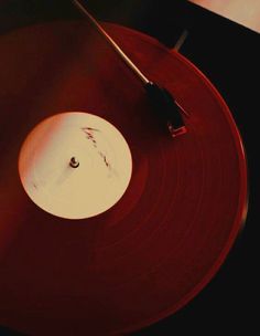 a record player's turntable with a red vinyl cover and white disc in the foreground