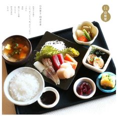 a tray with rice, sushi and other foods in bowls on top of it