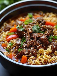 a bowl filled with beef and noodles on top of a table