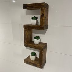 three wooden shelves with plants on them in a white walled room, one is made out of wood and the other has two small potted succulents