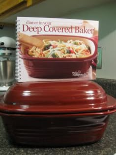 a cookbook is sitting on top of a casserole dish in the kitchen