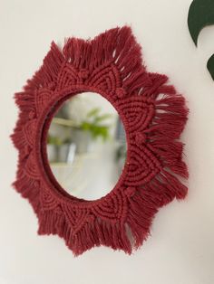 a round mirror hanging on the side of a white wall next to a green plant