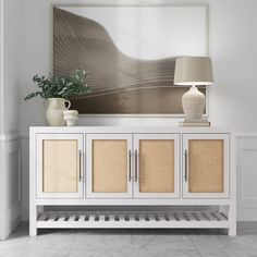 a white sideboard with two doors and three drawers in front of a painting on the wall