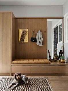 a dog laying on the floor in front of a wooden bench with coat rack above it