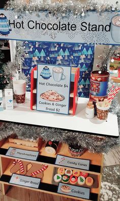 hot chocolate stand with cookies and gingerbreads on display in front of christmas trees