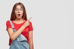 a girl with glasses making a funny face and pointing at something in front of her