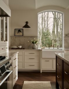 a kitchen with an arched window and white cabinets