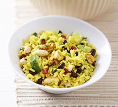 a white bowl filled with rice and nuts on top of a table next to a cup