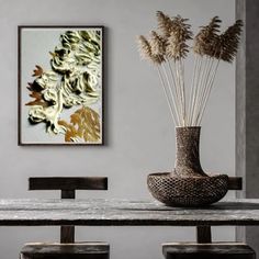 a vase filled with dry grass sitting on top of a table next to two wooden chairs