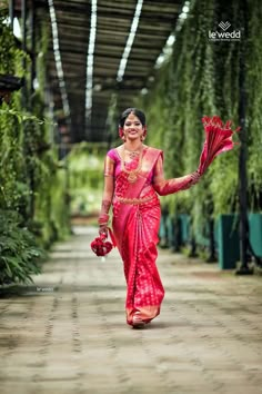 a woman in a red sari walking down a dirt road