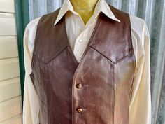 A 1970's vintage western vest crafted from a high quality soft brown leather. It has peaked front and back yokes, two front pockets and button closure. The inside is completely lined and this piece is in overall excellent condition. Size Medium Measurements: Chest: 102 cm / 40 inches Length: 63 cm / 25 inches Made in New York, USA. This item is one of a kind. BUYING VINTAGE: While all care is taken to state any obvious faults, please note that when you buy a vintage or preloved item, they may show small signs of ageing, wear and/or repair. Visit my website   https://phoenixmenswear.com.au/ Lots of fun stuff for guys and girls...!! Please note that if you are ordering from anywhere outside of Australia please add your phone number as it is now required for delivery.  Thanks much. Fitted Western Leather Vest, Brown Sleeveless Vest For Western-themed Events, Vintage Fitted Leather Vest, Retro Brown Vest For Workwear, Fitted Vintage Leather Vest, Retro Brown Vest For Work, Fitted Vest For Western-themed Events In Fall, Classic Brown Leather Vest, Brown Leather Vest For Workwear