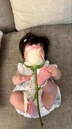 a baby sitting on a couch holding a rose