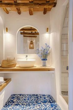 a bathroom with blue and white tiles on the floor, sink and mirror in it