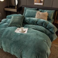 a teal colored bed with pillows on top of it and a cup in the middle