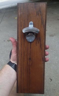 a person holding a wooden door handle with a metal latch on it's side