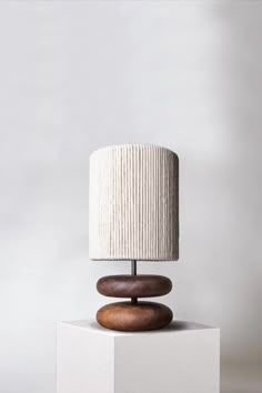 a table lamp sitting on top of a white block with a wooden base and fabric shade