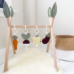 a baby crib with vegetables hanging from it's sides and a basket on the floor next to it