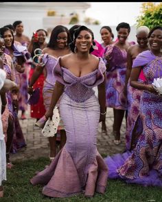 a group of women dressed in purple dresses standing next to each other on the grass