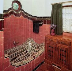 a bathroom with red tiles and a mirror on the wall next to a wooden cabinet