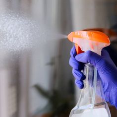 a person in blue gloves is spraying something out of a bottle