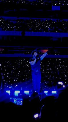 a man standing on top of a stage with his arms in the air while holding a microphone