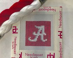 a needle and thread on top of a piece of cloth with the letter k in it