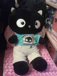 a black cat stuffed animal sitting on top of a bed