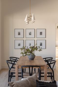 a dining room table with chairs and pictures on the wall