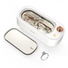 a pair of glasses sitting inside of a white case next to a ring and two other items