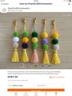 six pom pom key chains hanging on a wooden table with different colored tassels