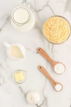 ingredients to make cheese pizza laid out on a marble counter top with measuring spoons