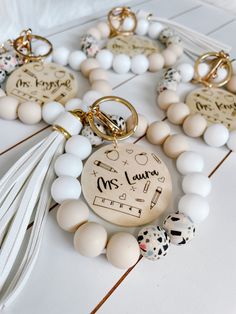 a white and black beaded bracelet with personalized charms on it, along with two tassels