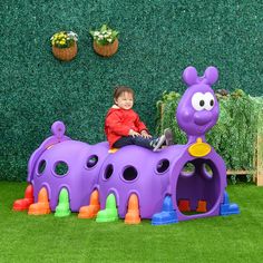 a little boy sitting on top of a purple toy train