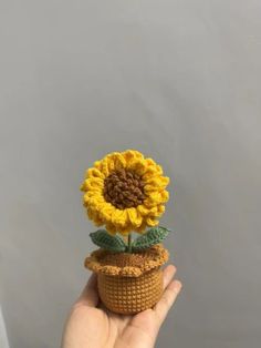 a crocheted sunflower sitting on top of a pot with leaves in it