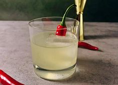 a glass filled with liquid and a red pepper on the side