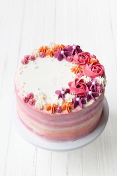 a cake with pink and orange flowers on it sitting on a white table next to a knife