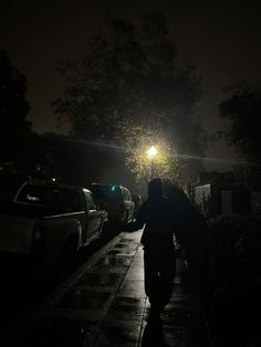 a person walking down a sidewalk at night