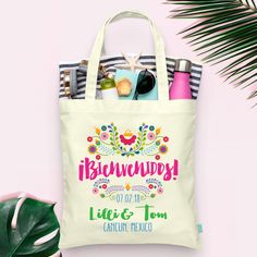 a tote bag with personalized items on it next to a palm leaf and plant