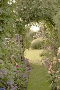 a garden with lots of flowers on the side of it and an archway in the middle