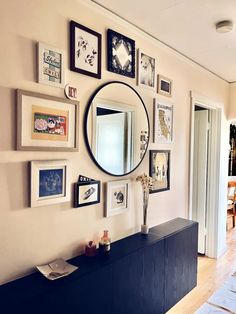 a living room with pictures on the wall and a large round mirror hanging above it