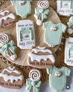 baby shower cookies decorated with blue and brown icing on a wooden platter, including ones that say it's in the oven